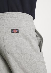 Pantaloni sportivi grigi realizzati in misto cotone, con vita elasticizzata, tasche laterali e un logo quadrato applicato sulla tasca posteriore.