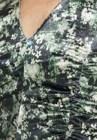 Blumenmuster Kleid mit tiefem V-Ausschnitt, in einer Mischung aus grünen, weißen und blauen Farbtönen, aus einem gathering-seidigen Stoff.