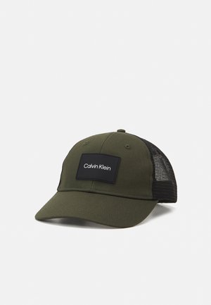 Oliwkowa czapka z daszkiem z czarną siateczką z tyłu i czarną naszywką z przodu z napisem „Calvin Klein” białym tekstem.
