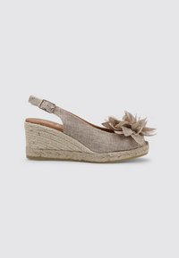 Chaussure compensée en espadrille beige avec un design à bride arrière, supérieure en tissu texturé et accent décoratif en forme de fleur près des orteils. Talon en jute tressé.