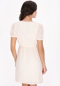 Cremfarbenes, strukturiertes Minikleid mit kurzen Puffärmeln, elastischem Bund und lockerer Passform, das ein Karomuster aufweist.