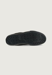 Suela de zapatilla negra con una superficie de goma texturizada con un patrón de espiga y un borde liso. Incluye marca en el costado.