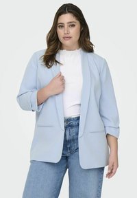 Hele sinine bleiser, millel on mugav lõige, sisselõigatud krae ja kolmveerandikkused varrukad. Kandnud valge ribaga topi ja kõrge vöökohaga teksade peal.