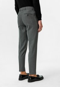 Grijze op maat gemaakte broek met een rechte snit, voorzien van een achterzak, en gecombineerd met glanzende zwarte instappers. Zachte stofstructuur duidelijk zichtbaar.