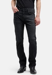 Ciemne dżinsy z prostą nogawką, posiadające klasyczny, pięciokieszeniowy design, subtelne przeszycia oraz zapięcie na guziki.