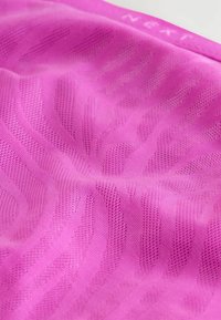 Roze sportstof met een gestructureerd patroon, featuring subtiele golven en een ademend mesh-design. Rekbaar en lichtgewicht materiaal.