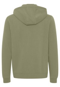 Felpa verde oliva con zip frontale, grande cappuccio e polsini a costine. Il tessuto appare liscio con dettagli di cucitura minimi.