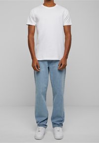 Vit bomullströja med korta ärmar, kombinerad med ljusblå denimjeans och vita sneakers. Enkel design, avslappnad passform och utan mönster.