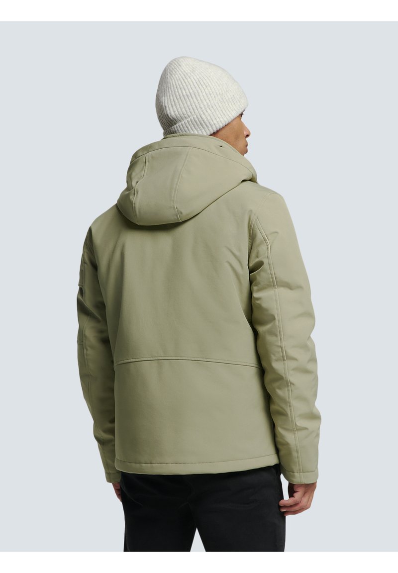 Blouson rembourré vert clair avec capuche, présentant une texture lisse et des détails cousus, associé à un bonnet en tricot blanc.