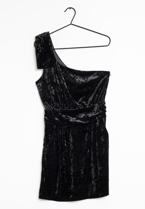 Vestito in velluto nero monospalla con spallina larga, vita aderente e lunghezza corta appeso a una sottile gruccia nera su sfondo bianco.