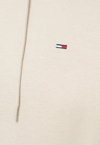 Μπεζ φούτερ με υφή πλεκτού υφάσματος. Διαθέτει μικρό, κεντημένο λογότυπο σε μπλε, λευκό και κόκκινο στη αριστερή πλευρά του στήθους.