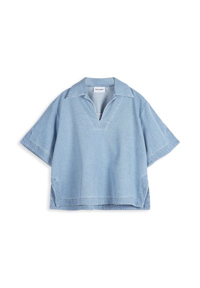 Chemise en jean bleu clair à manches courtes avec un large col, une ouverture en V et des fentes sur les côtés, posée à plat sur fond blanc.