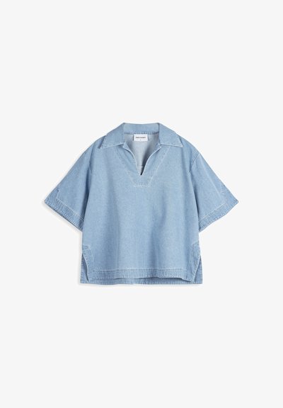 Chemise en jean bleu clair à manches courtes avec un large col, une ouverture en V et des fentes sur les côtés, posée à plat sur fond blanc.