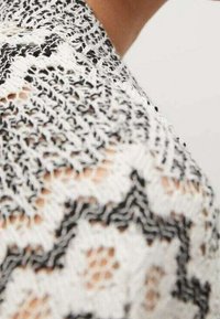 Sweter dzianinowy z czarno-białym wzorem zygzaka, o fakturze z otwartym splotem i miękkiej, lekkiej włóczce.