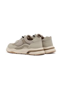 Zapatillas beige con parte superior de malla texturizada y cuero liso, punta redondeada, suela de goma y acentos en marrón claro en contraste.