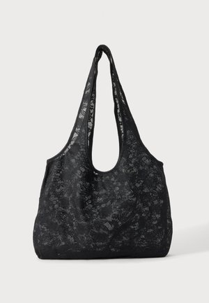 Sort blonde skuldertaske med bred rem og afrundet rektangulært design, med blomstret blondemønster på ensfarvet baggrund.