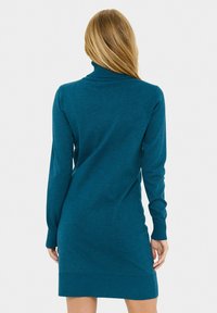 Abito lavorato a maglia color teal con collo alto a barchetta, maniche lunghe e polsini e orlo a costine. Tessuto liscio e silhouette aderente.