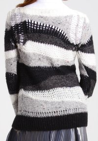 Pull tricoté avec des rayures horizontales en noir, gris et blanc. Comprend des sections à mailles ouvertes, un tricot texturé et une silhouette décontractée.
