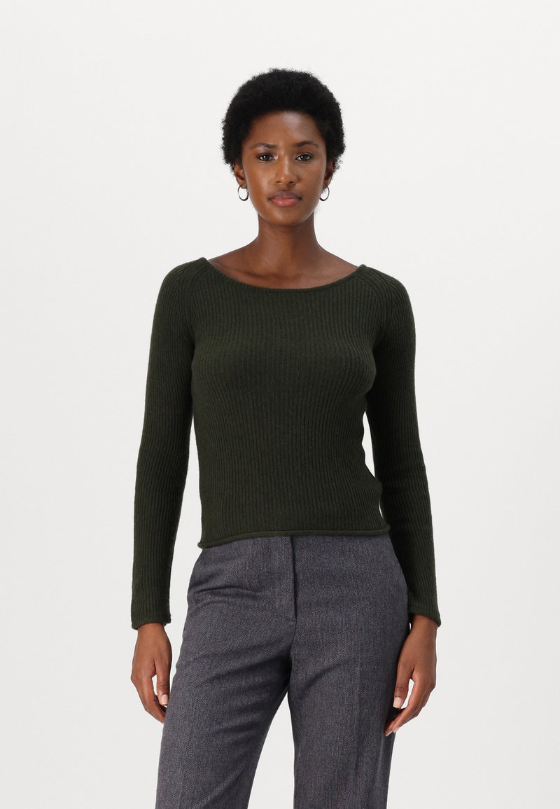 Pull en maille côtelée vert foncé avec un large col, des manches longues et une silhouette ajustée, associé à un pantalon gris texturé.