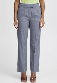 Pantalons gris, ajustés avec une jambe droite, devant plissé et fentes sur les côtés à l'ourlet. Fabriqués en tissu texturé avec une finition lisse.