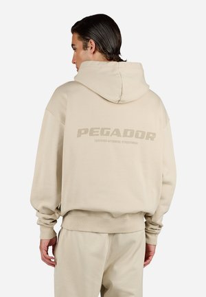 Beige hoodie with a large "PEGADOR" logo on the back. Made of soft material, features a spacious hood and ribbed cuffs.