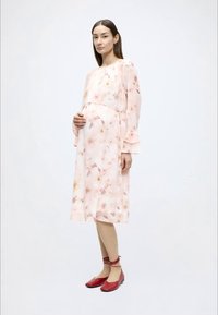 Φλοράλ ροζ midi φόρεμα με μακριά, βολάν μανίκια. Το μοντέλο φορά κόκκινα φλατ παπούτσια με δέσιμο στον αστράγαλο. Απαλό, ελαφρύ ύφασμα.