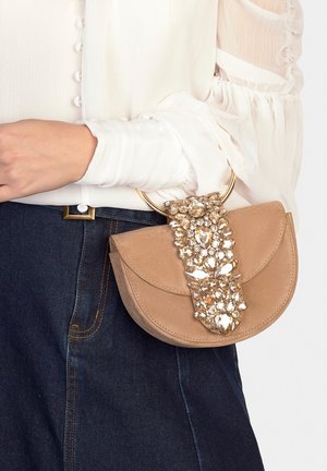 Borsa in camoscio color taupe con ferramenta circolare dorata e decorazioni in cristallo sulla pattina. Presenta una texture liscia e una forma arrotondata.