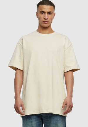 Beige oversized t-shirt made of soft cotton, featuring short sleeves, a round neck, and a relaxed fit with minimal stitching details.