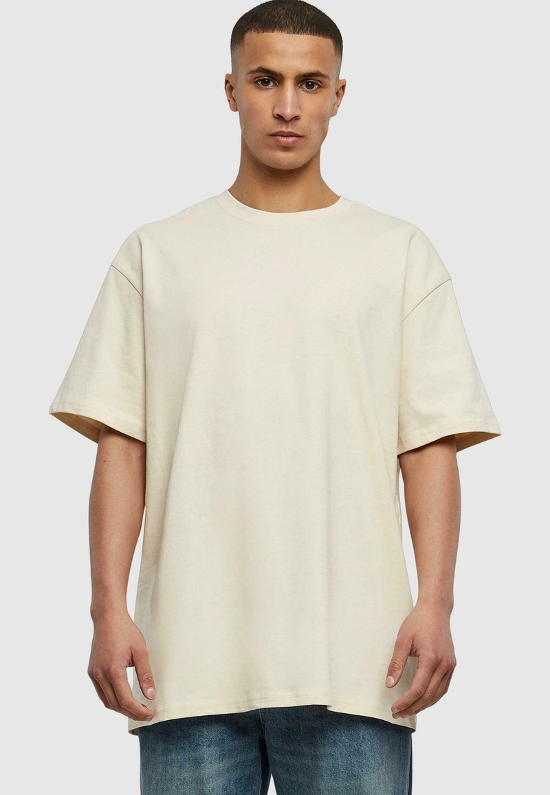 Beige overdimensjonert t-skjorte laget av myk bomull, med kortermede ermer, rund hals og en avslappet passform med minimalt med sømdetaljer.