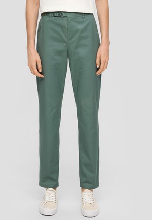 Groene chino's met een ontspannen pasvorm, voorzien van een plat front, riemlussen en zijzakken. Gecombineerd met beige sneakers voor een casual uitstraling.
