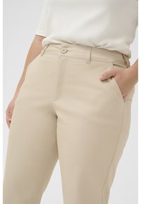 Beige tailored trousers with a flat front, side pockets, and a single button closure. Smooth texture and straight-cut design.