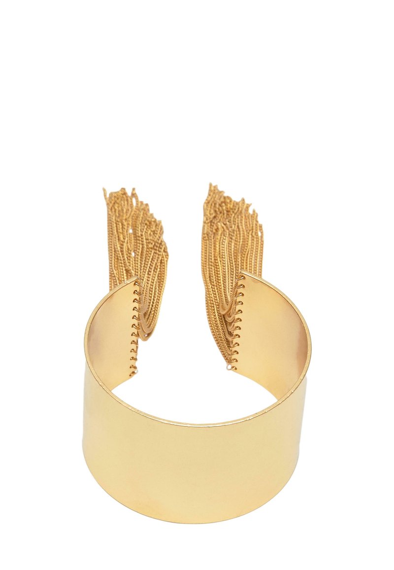 Kultainen panta rannekoru, jossa on sileä ja kiillotettu pinta. Seinillä roikkuvat frangipani-ketjut lisäävät tekstuuria ja ulottuvuutta. Yksinkertainen, avoin muotoilu.