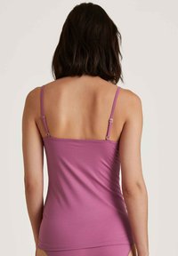 Purple camisole with adjustable straps, smooth texture, fitted design, and a straight hem, displayed from the back.