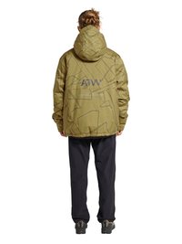 Person mit geflochtenem Haar, die eine olivgrüne Kapuzenjacke mit abstrakten Mustern und schwarze Hose trägt, steht mit dem Rücken zur Kamera auf weißem Hintergrund.