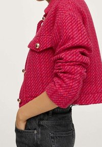 Fuksjowa kurtka typu cropped z teksturowanym wzorem, złotymi guzikami i kołnierzem. Posiada boczną kieszeń oraz dopasowane długie rękawy.