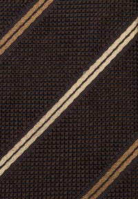 Tessuto con un design intrecciato marrone scuro e strisce diagonali in beige e beige chiaro. La trama è ruvida con motivi di filo visibili.