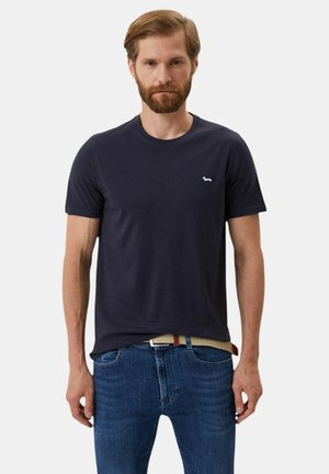 T-shirt a maniche corte blu navy in morbido cotone. Presenta un piccolo logo ricamato sul petto. Abbinato a jeans blu.