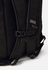 Zaino nero con spallacci in rete imbottita, fibbie regolabili e un'etichetta con logo. Tessuto testurizzato con accessori in metallo durevoli.