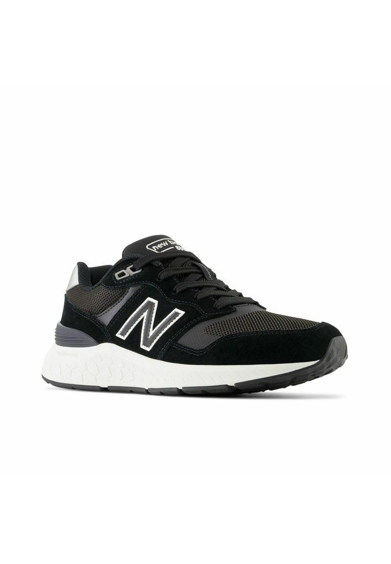 Chaussure de sport noire en cuir suédé et en mesh, avec une pointe arrondie, une semelle rembourrée et un intercalaire blanc à motifs hexagonaux.