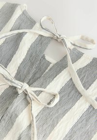 Stof met verticale blauw-witte strepen en een gestructureerd oppervlak. Voorzien van een striksluiting en een open neklijn.