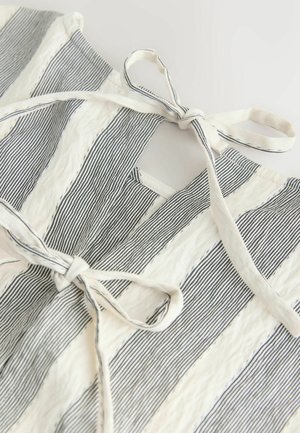 Randigt tyg med blå och vita lodräta linjer och en texturerad yta. Har en knytstängning och en öppen halsdesign.