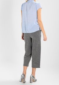 Light blue short-sleeve shirt with vertical stripes, paired with gray textured cropped pants and silver high-heeled shoes.