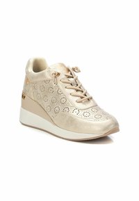 Sneakers a zeppa beige con design floreali perforati, realizzati in pelle liscia, punta arrotondata e suola bianca testurizzata. Accentuati da dettagli in oro.