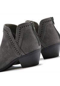 Botines de ante gris con un tacón bajo, que presentan detalles troquelados a lo largo de los bordes y un cierre con cremallera en la parte trasera.