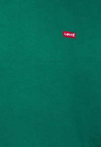 Zielona bawełniana koszulka z prążkowaną strukturą, z małym czerwonym logo Levi's wyszytym z przodu. Prosty krój, krótkie rękawy.