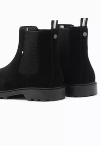 Botas tobilleras de ante negro con paneles laterales de malla, inserciones elásticas y una suela de goma robusta. Presenta una asa de tirar y acentos de logo.