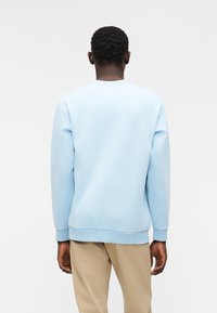 Φωτεινό γαλάζιο φούτερ με στρογγυλή λαιμόκοψη και μακριά μανίκια, κατασκευασμένο από μαλακό ύφασμα. Διαθέτει ριμπ μανσέτες και τελείωμα, ομαλή υφή και απλό σχέδιο.