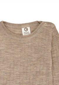 Lichtbruine lange mouw shirt met geribbelde textuur, voorzien van een ronde hals en een klein drukknopje op de schouder. Het label draagt de tekst "müsli."