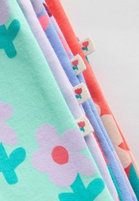 Behajtott szövet színes virágmintákkal zöld, lila, kék és piros árnyalatokban, mindegyiken kis címkék piros virág motívummal.