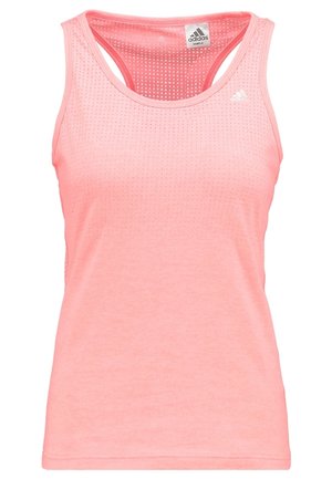 Vrouw in een roze mouwloos topje, zwarte joggingbroek en witte sneakers die loopt of jogt tegen een effen lichte achtergrond.